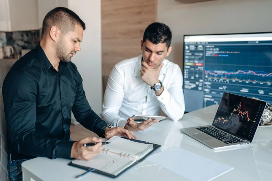 A contemporary workspace featuring hands reviewing marketing data on a laptop alongside paper documents.